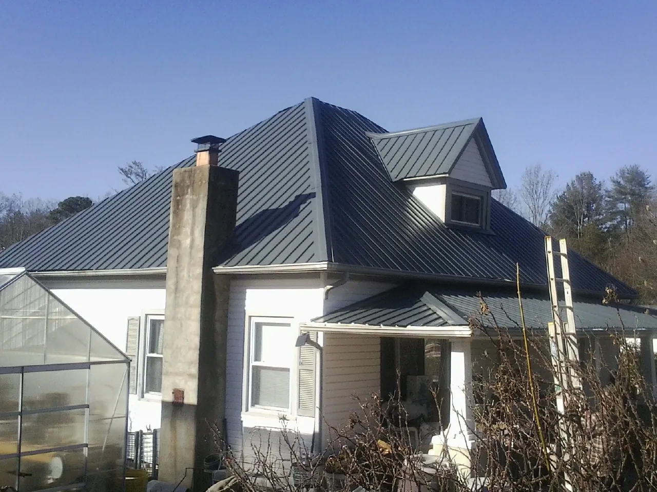 Dark blue standing seam metal roof on a white farmhouse with dormer — Slate & Tile Roof Repair by Roofing Brothers in Ladson
