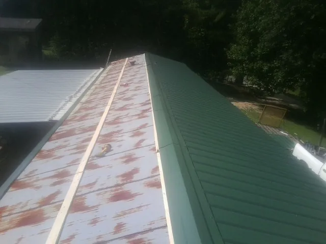 Old rusted panels beside newly installed green metal roofing — Wind Damage Roof Repair by Roofing Brothers in Ladson