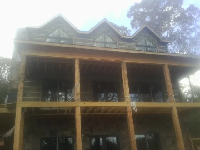 Dormers and porch framing on a large log home under construction — Roof Coating work by our crew in Ladson