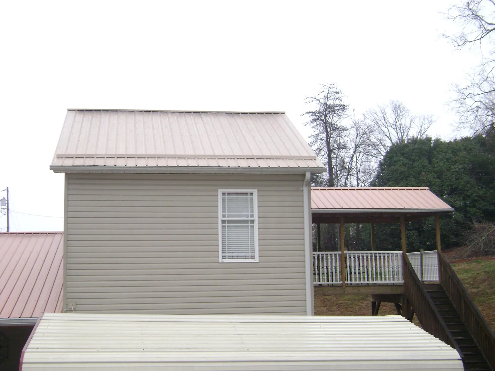 Tan metal roofs on a two story addition and attached porch, from a Roof Replacement job in Ladson