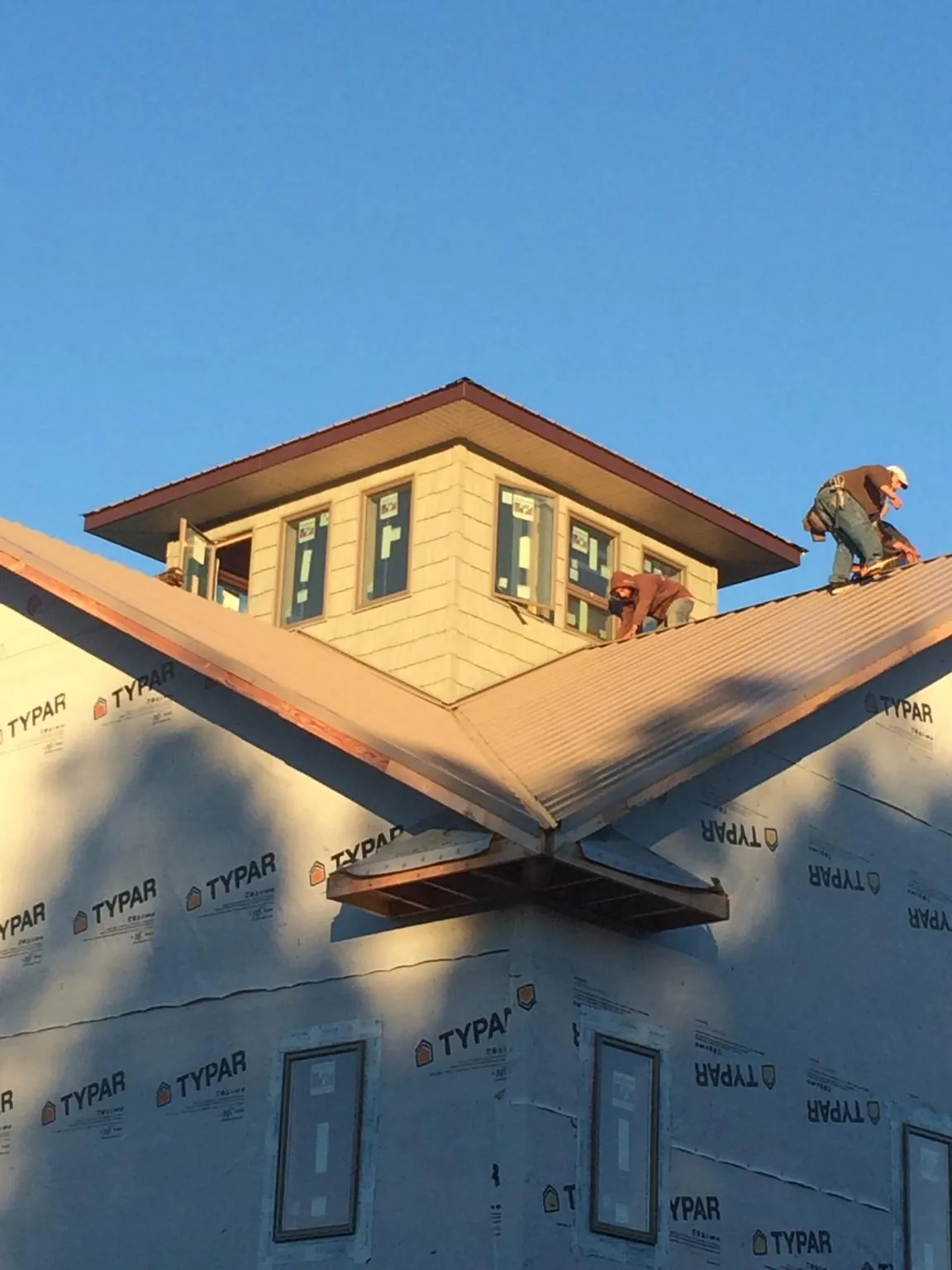 Roofers working around a rooftop cupola on a new metal roof at sunset — Roof Waterproofing in Ladson by Roofing Brothers
